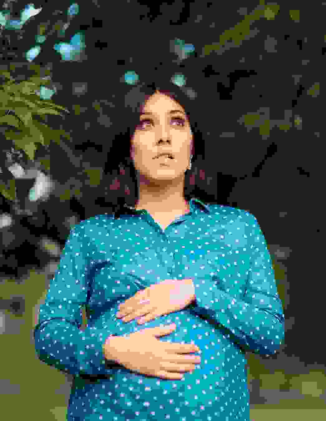 Une femme se tient le ventre et semble malheureuse. L’image symbolise la peur et la détresse causées par la tokophobie, une peur pathologique de l’accouchement.