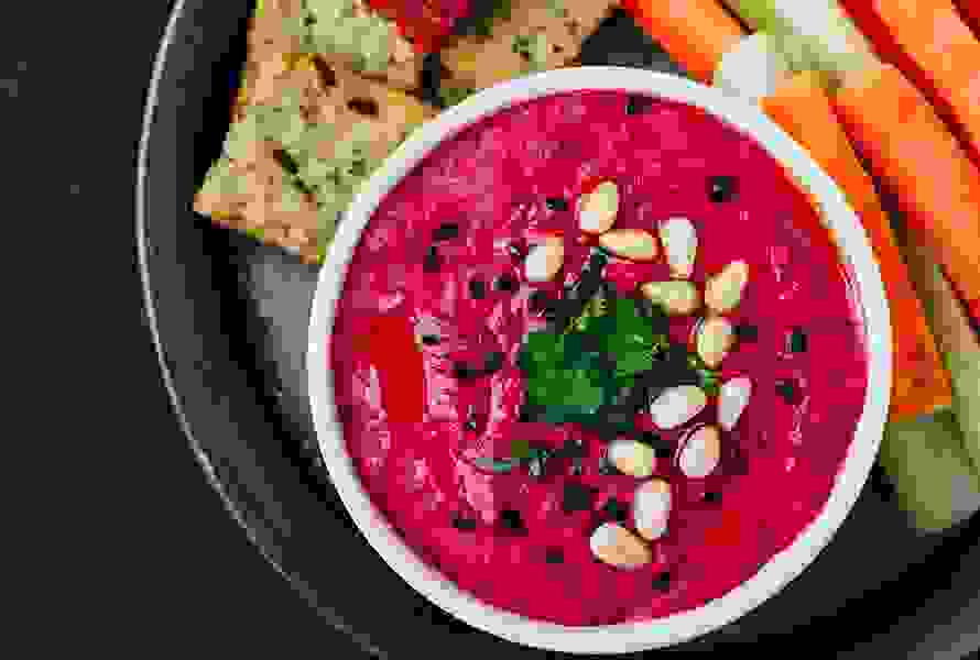 Eine Schüssel mit Randenhummus und Crackern – gesunde Alternativen bei Heisshunger in der Spätschwangerschaft.