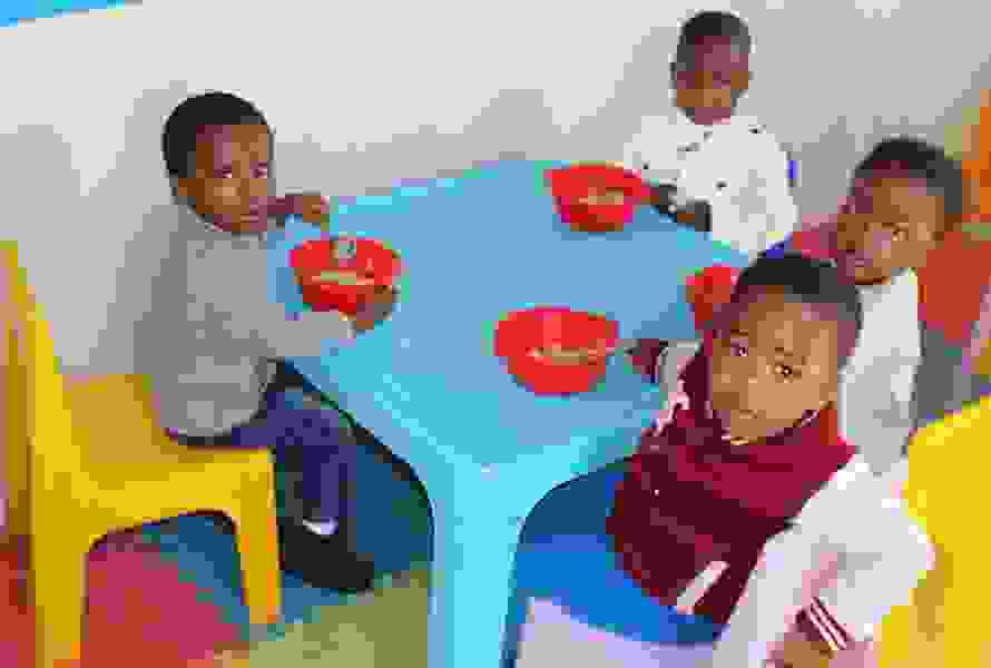 Die Kinder der KITA Nkululeko essen gemeinsam am Plastiktisch. Die ausgewogene Ernährung gehört zur täglichen Basis für Lernen und Wachsen.