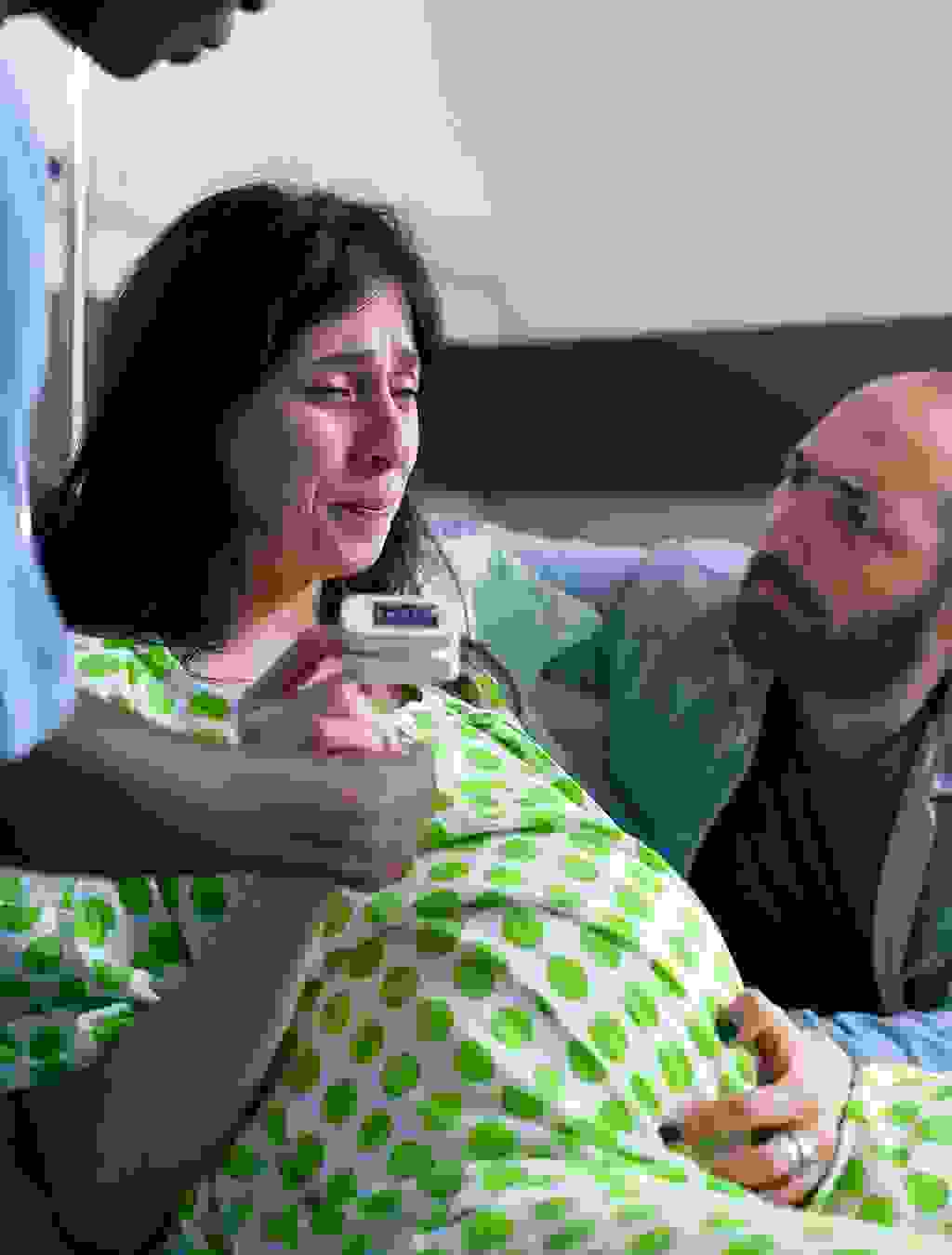 Eine Frau in den Wehen stützt sich ab, ihr Partner kniet neben ihr und gibt ihr Halt – ein emotionaler Moment kurz vor der Geburt.