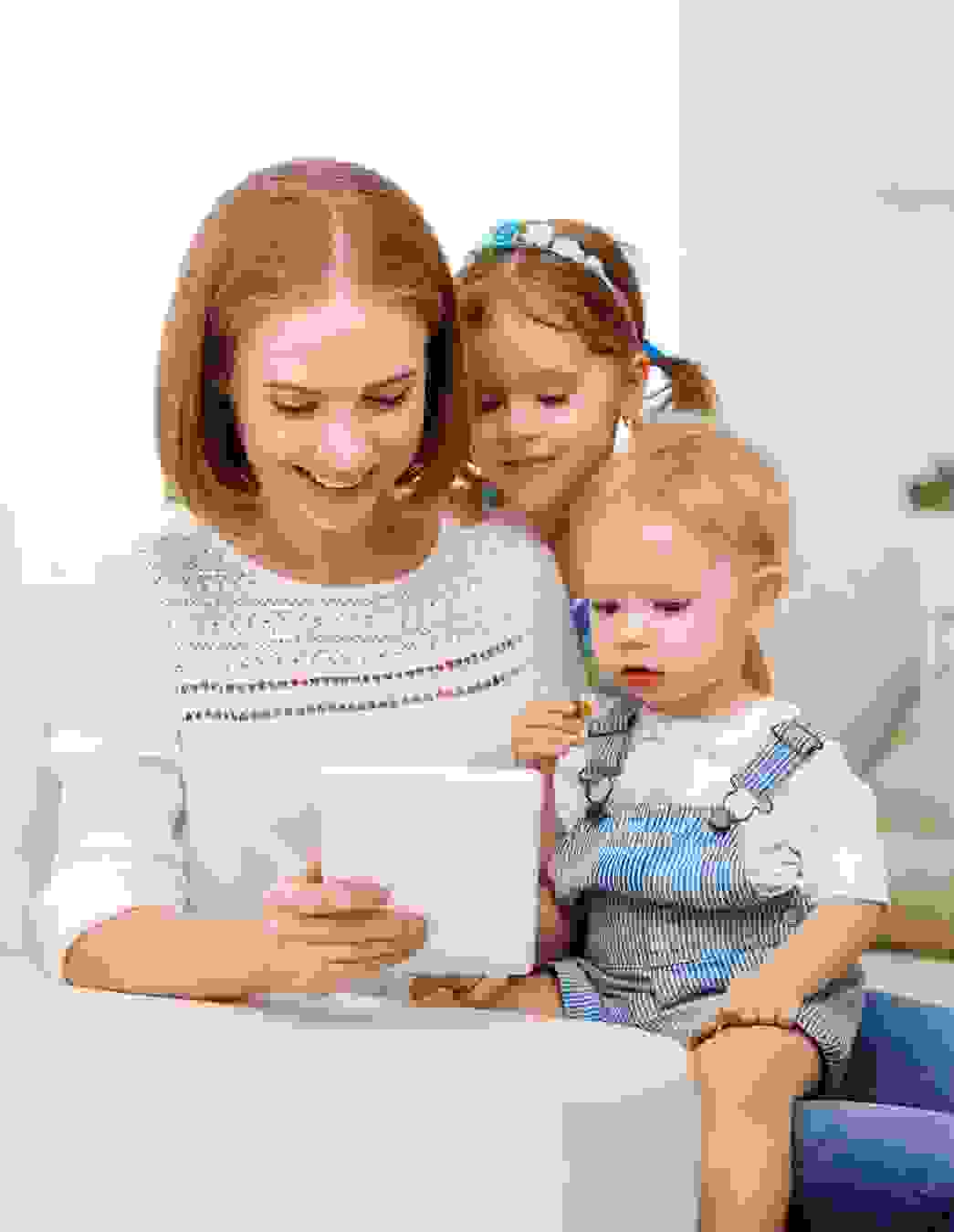 Una giovane madre guarda un tablet con i suoi figli – come socio PRO LIFE, le famiglie hanno accesso a sconti esclusivi sulle assicurazioni complementari.