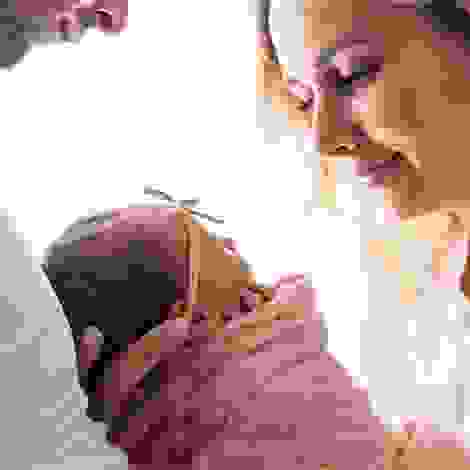 Ein glückliches Paar schaut liebevoll auf das Neugeborene in den Armen der Mutter – ein emotionaler Moment nach einer langen Reise voller Vorfreude und Geduld.