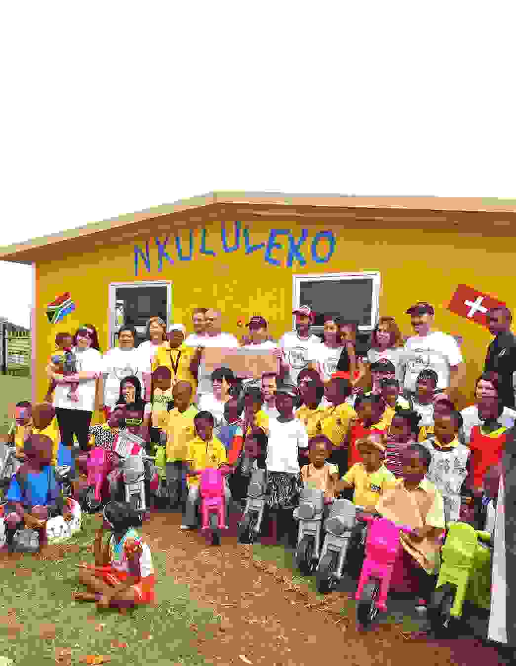 Das Bauteam steht gemeinsam mit den Kindern von Nkululeko stolz vor dem neu errichteten Gebäude – ein Moment voller Hoffnung und Zusammenhalt.