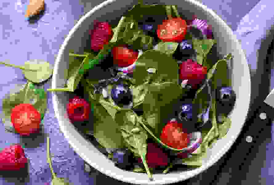 Un’insalata fresca con spinaci, mirtilli, lamponi e pomodori è un pasto leggero e ricco di folati – ideale per il menu quotidiano.


