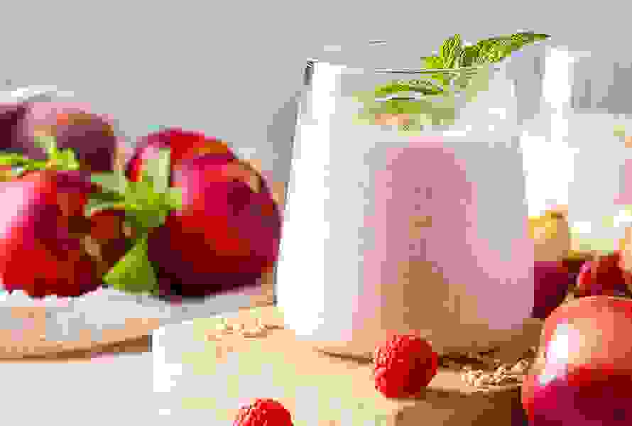 Ein frisches Glas Smoothie mit Himbeer- und Pfirsichgeschmack – lecker, gesund und ideal für die Flüssigkeitsaufnahme in der Schwangerschaft.