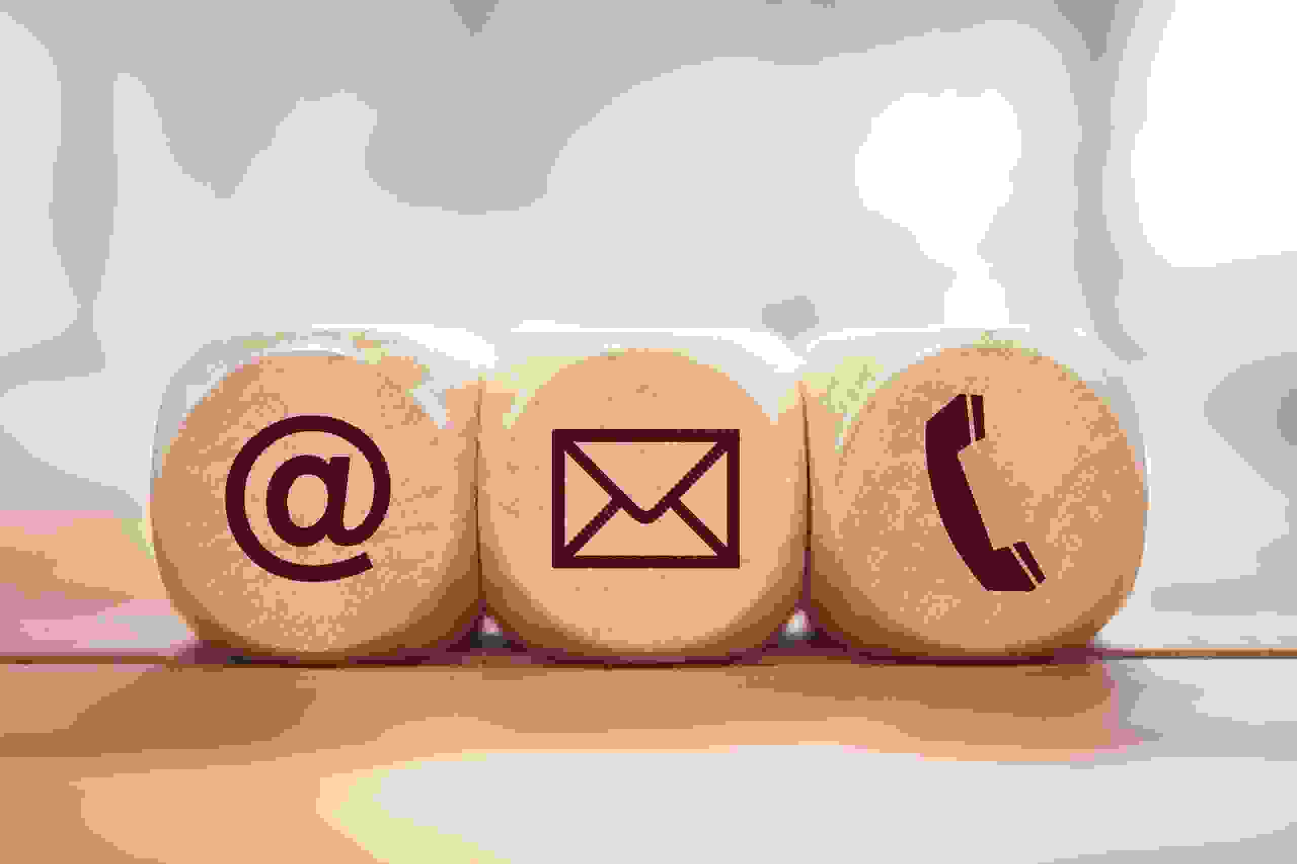 Tre cubi di legno con i simboli di e-mail, posta e telefono rappresentano la facilità di contatto e il servizio personale.