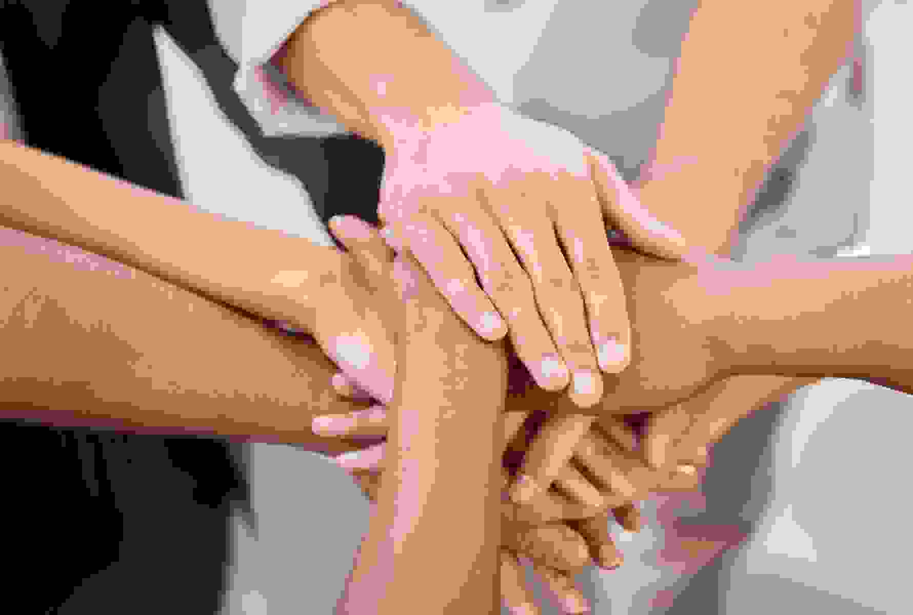 Un gruppo di persone sta in cerchio e sovrappone le mani al centro – un forte segno di comunità, fiducia e solidarietà.