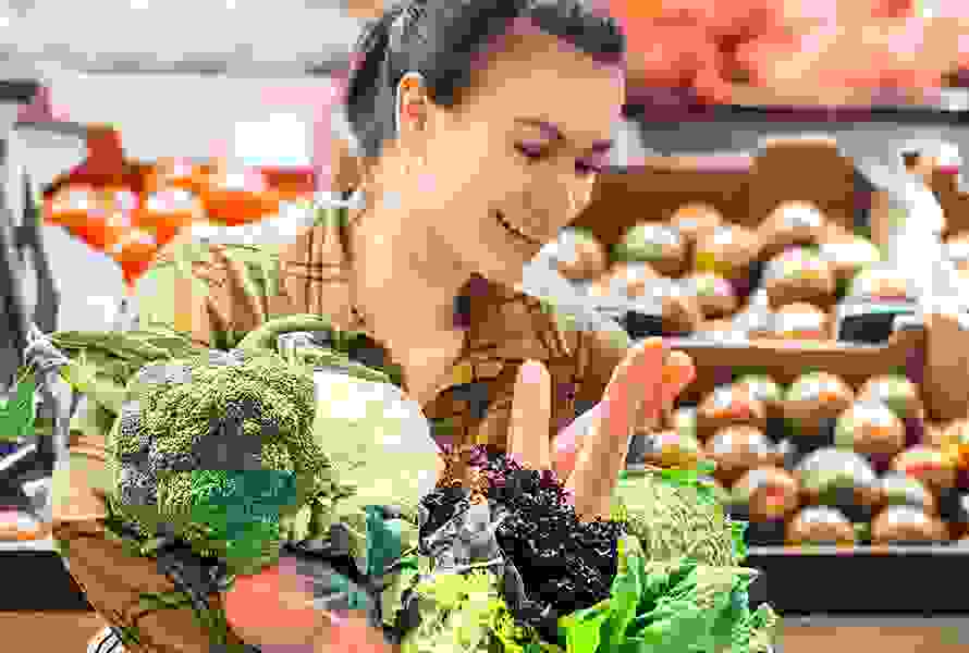 Eine Frau wählt frisches Gemüse wie Broccoli, Blumenkohl und Rüebli – Grundlage für eine ausgewogene Ernährung in der Schwangerschaft.