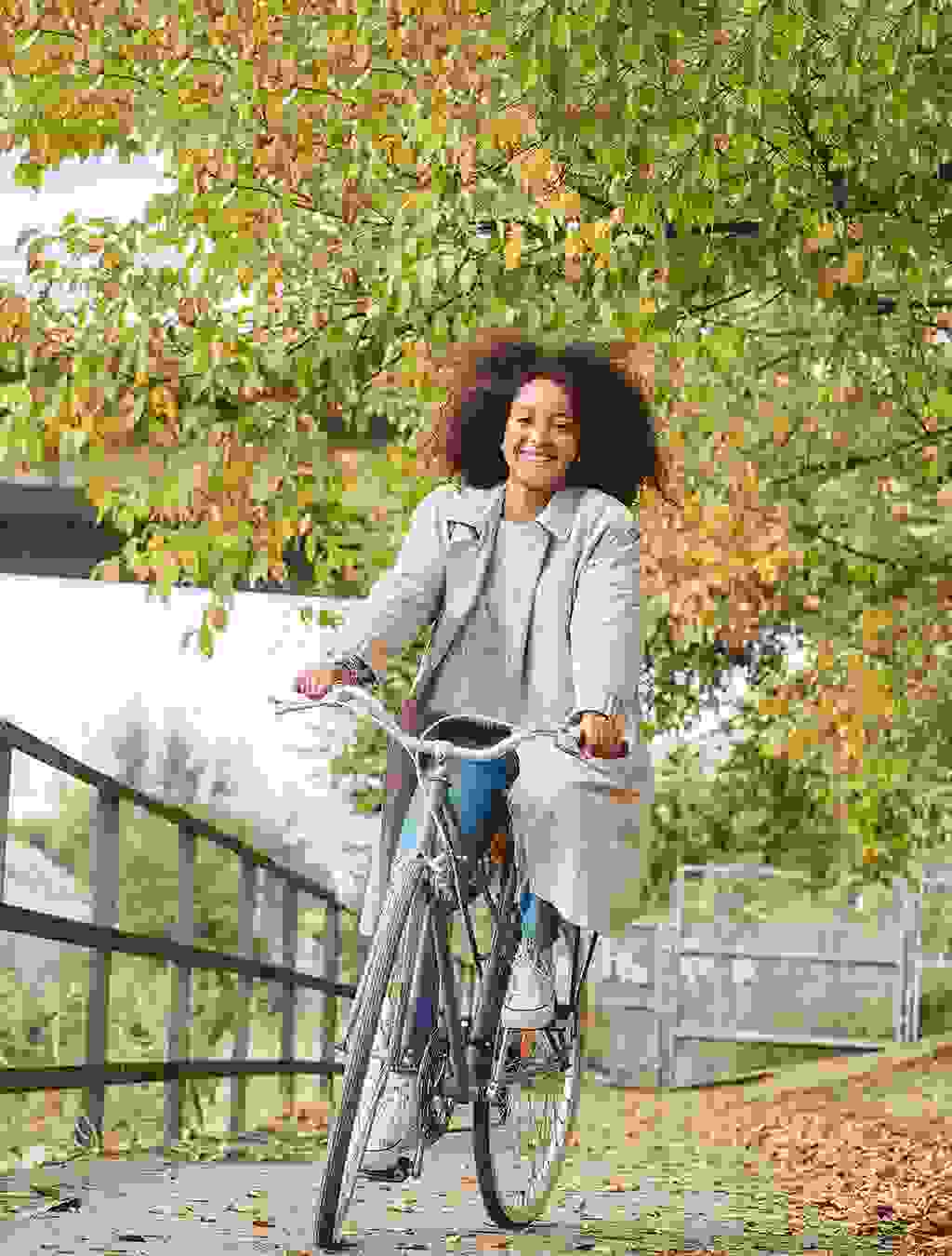 Eine strahlende junge Frau fährt entspannt Fahrrad – Bewegung an der frischen Luft stärkt Körper und Geist während der Schwangerschaft.