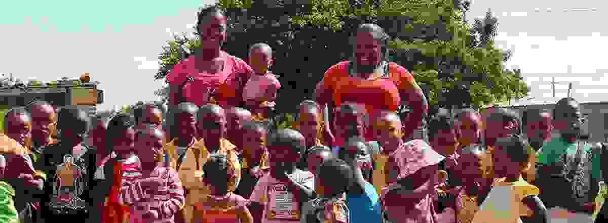 Kinder der Kita Nkululeko lachen gemeinsam mit zwei Betreuerinnen – ein Ort voller Wärme, Bildung und Hoffnung mitten in Orange Farm.