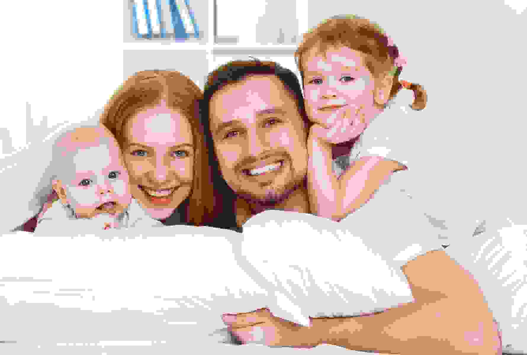 Une famille composée d’un père, d’une mère et de deux enfants sourit à la caméra – symbole de cohésion et de joie de vivre.