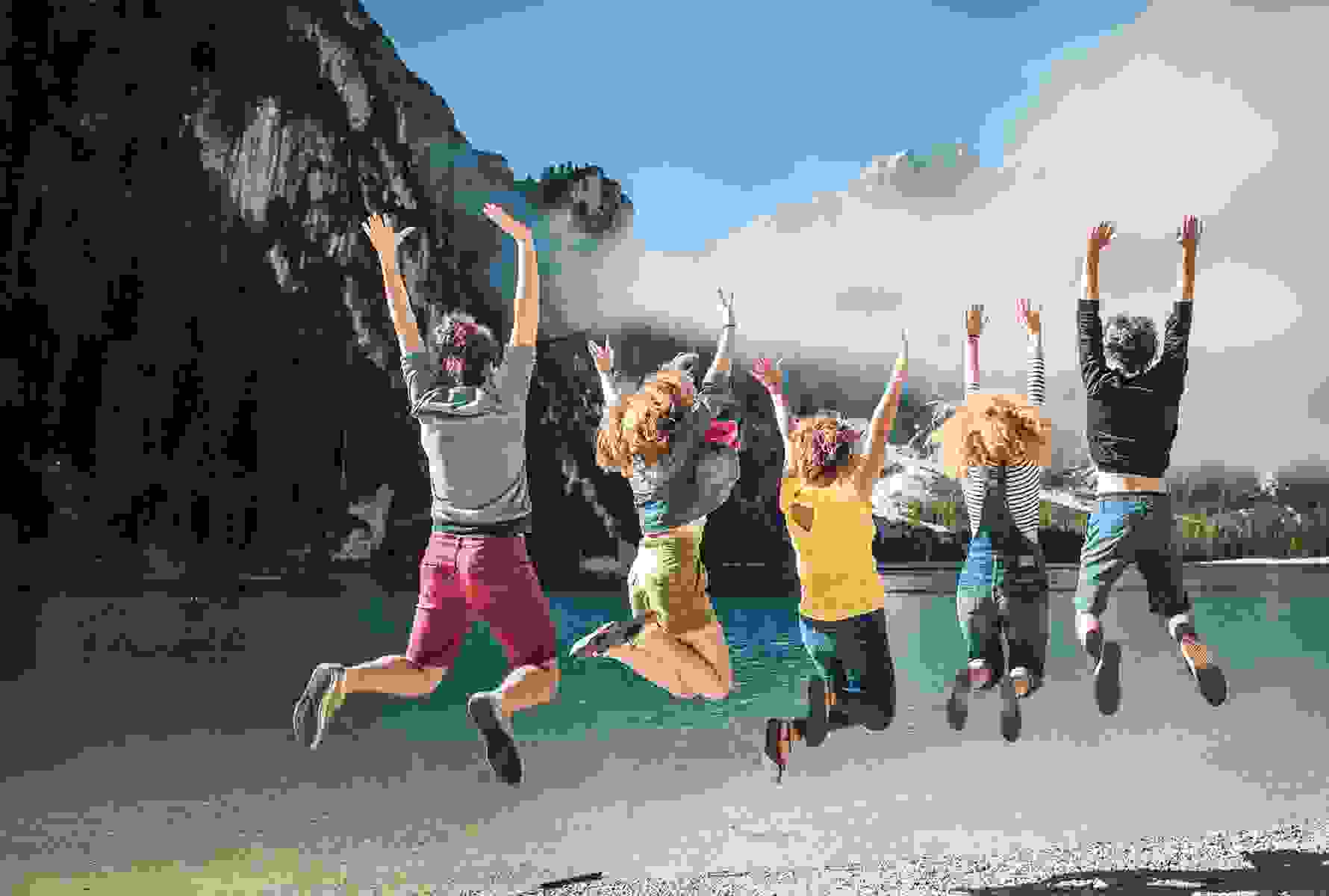 Un groupe de jeunes saute en l’air au bord d’un lac de montagne – une image de liberté, de joie de vivre et des avantages loisirs pour les membres PRO LIFE.