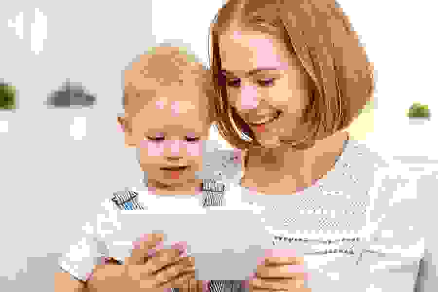 Una giovane donna mostra un tablet a un bambino – segno di sostegno, educazione e vicinanza digitale.