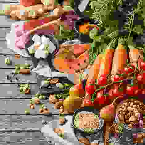 Eine bunte Auswahl an nährstoffreichen Lebensmitteln: rotes Fleisch, Lachs, Feta, Hülsenfrüchte, Gemüse und Obst – alles, was Mutter und Kind jetzt gut tut.