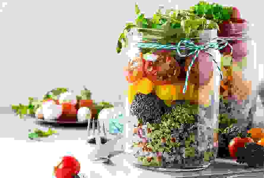 Ein bunt geschichteter Salat im Glas – praktisch und gesund für die schnelle Mittagspause, perfekt vorbereitet und frisch.