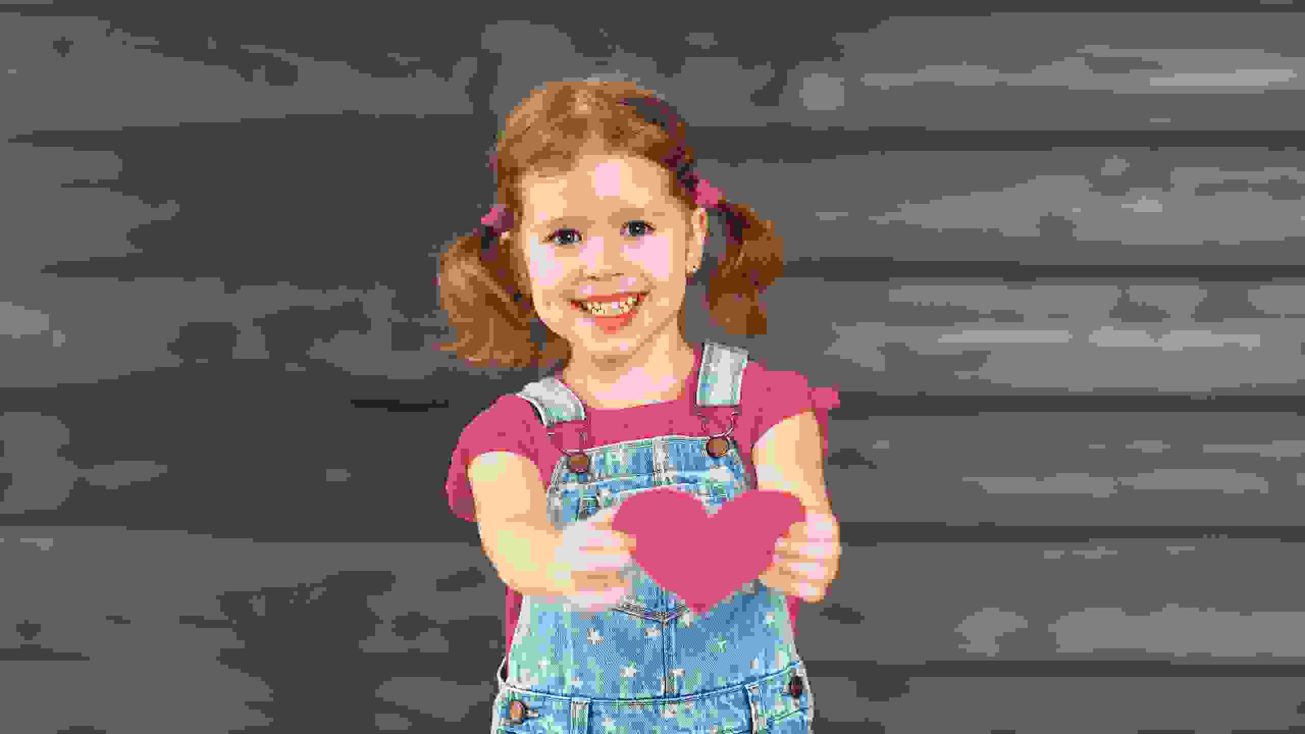 Una bambina porge un cuore verso la fotocamera – un forte simbolo di compassione e di vera solidarietà.