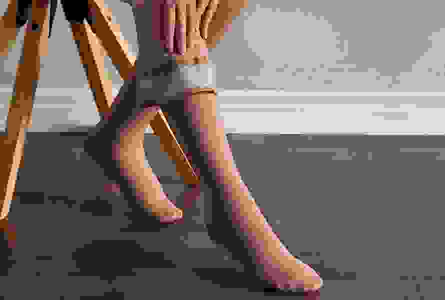Frau zieht Kompressionsstrümpfe an, die helfen, geschwollene Beine zu entlasten und das Thromboserisiko zu senken.