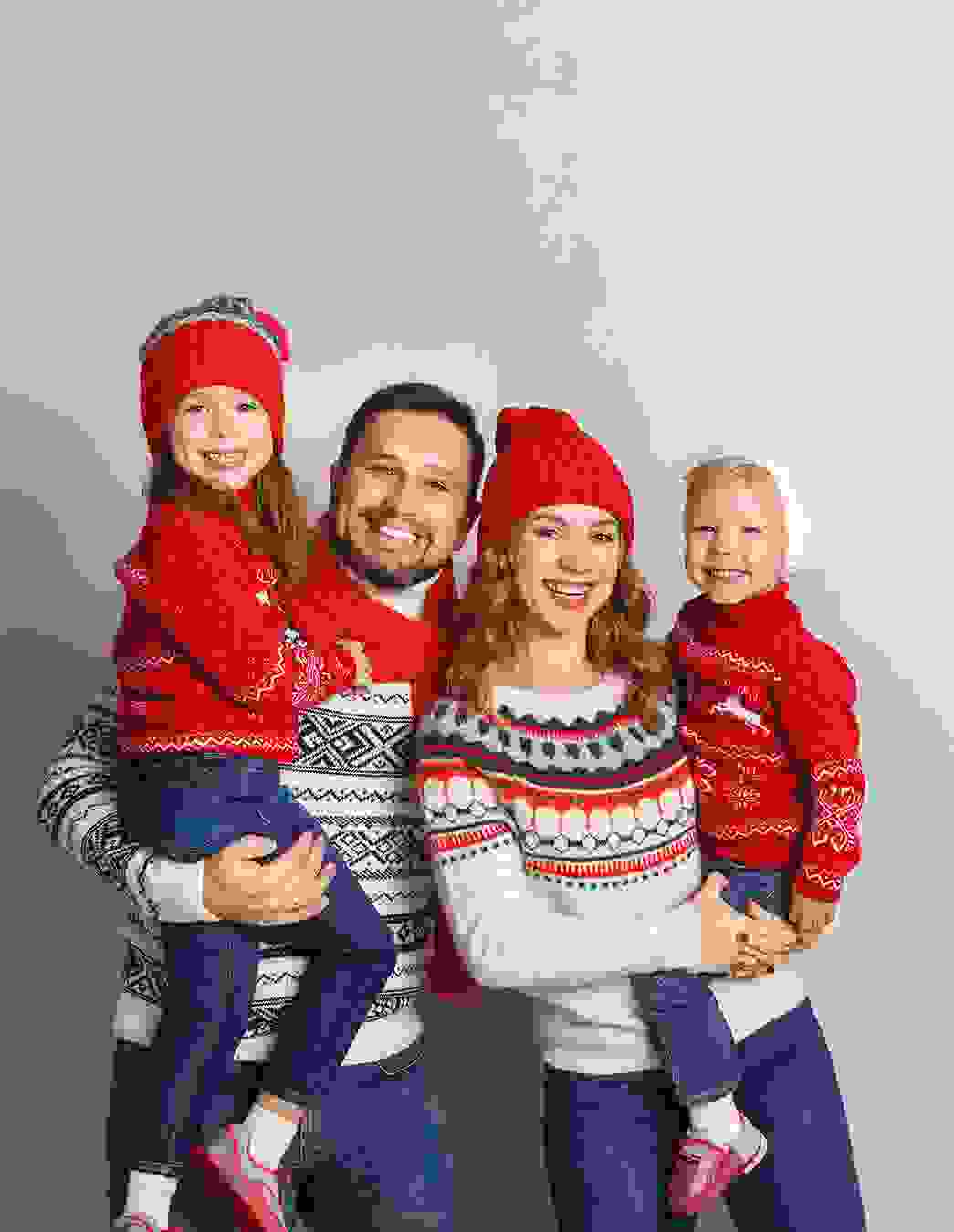 Eine vierköpfige Familie in Norwegerpullovern und Strickmützen geniesst gemeinsam die kalte Jahreszeit – ein Bild von Wärme, Zusammenhalt und Tradition.