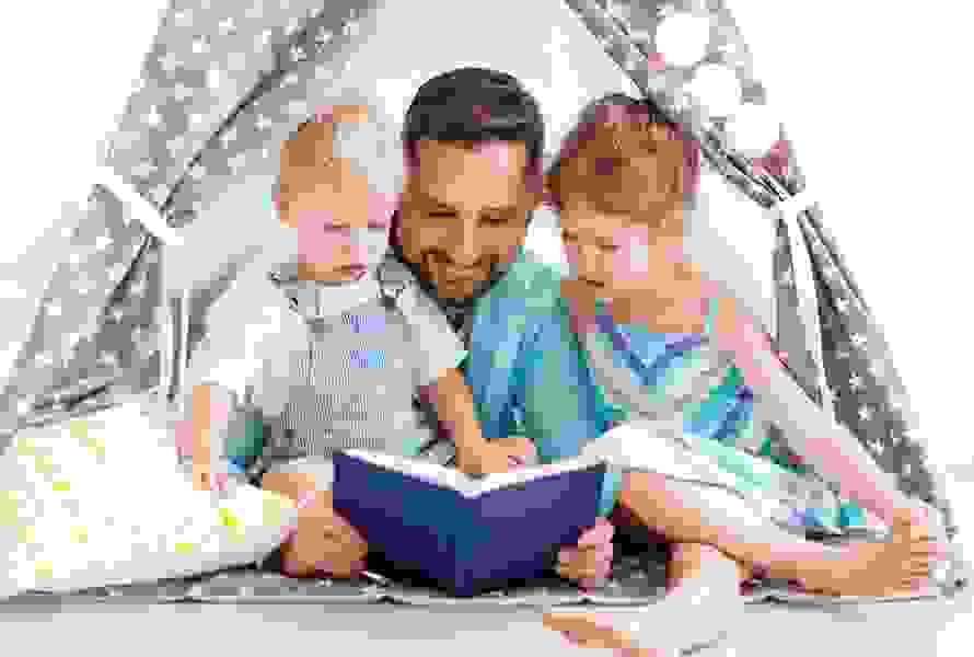 Ein Vater liest seinen Kindern im selbstgebauten Wohnzimmerzelt vor – ein Moment voller Geborgenheit, wie ihn PRO LIFE im Alltag möglich macht.