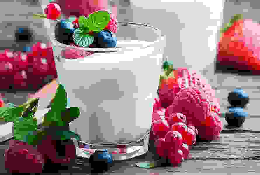 Ein Glas frischer Naturjoghurt mit Beeren als Topping – ein leckerer, sättigender Snack gegen Heisshunger, ohne unnötige Kalorien.