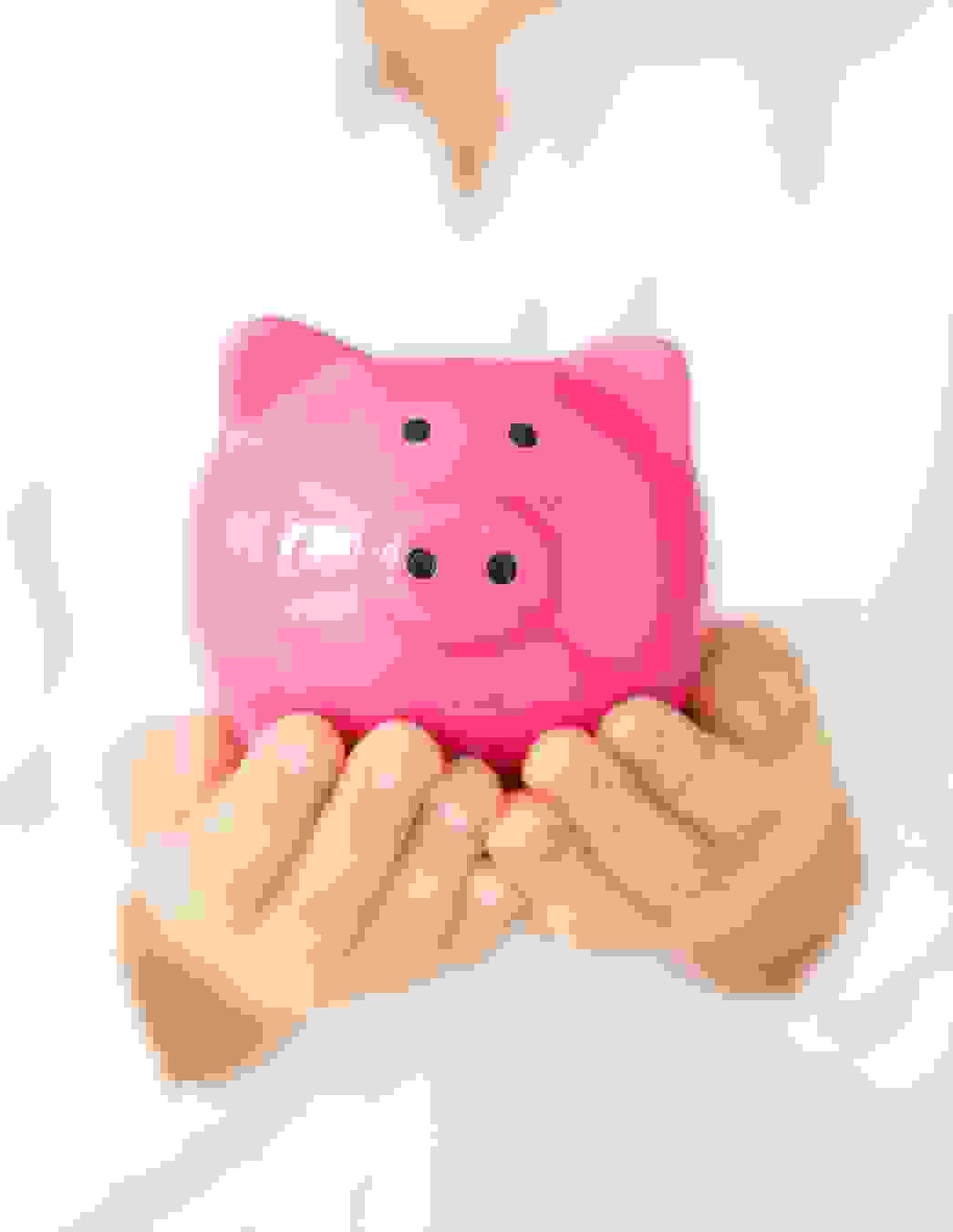 Une personne porte précautionneusement une tirelire rose sur ses paumes ouvertes – une image de vigilance, confiance et gestion durable de vos cotisations.