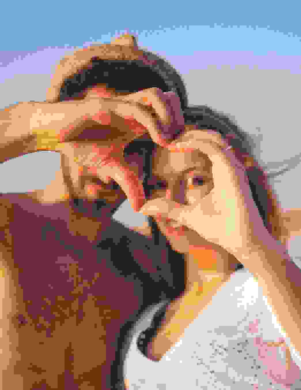 Glückliches Paar im Sonnenschein formt mit den Fingern ein Herz – ein Symbol für Zusammenhalt und Nähe in dieser besonderen Zeit.