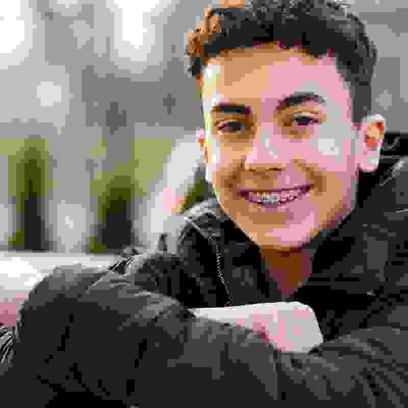 Un adolescente con l’apparecchio sorride alla fotocamera – PRO LIFE copre fino al 90 % dei costi dei trattamenti ortodontici.