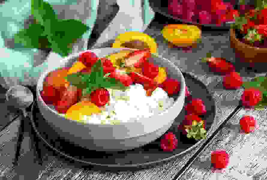 Eine Schale Hüttenkäse, liebevoll dekoriert mit Beeren und saisonalen Früchten – eiweissreich und angenehm leicht.