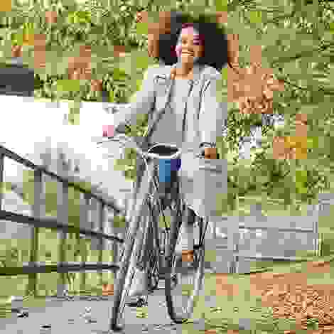 Eine strahlende junge Frau fährt entspannt Fahrrad – Bewegung an der frischen Luft stärkt Körper und Geist während der Schwangerschaft.