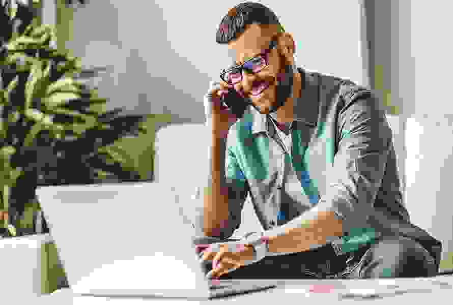 Un homme travaille concentré sur son ordinateur portable et téléphone – un contact simple pour vos demandes.