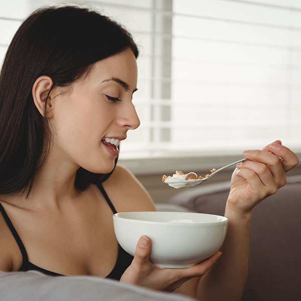 Ballaststoffreiche Ernährung bei Verstopfung in der Schwangerschaft Schwangere Person isst Müesli mit Löffel – ballaststoffreiche Ernährung unterstützt die Verdauung und hilft gegen Verstopfung in der Schwangerschaft.