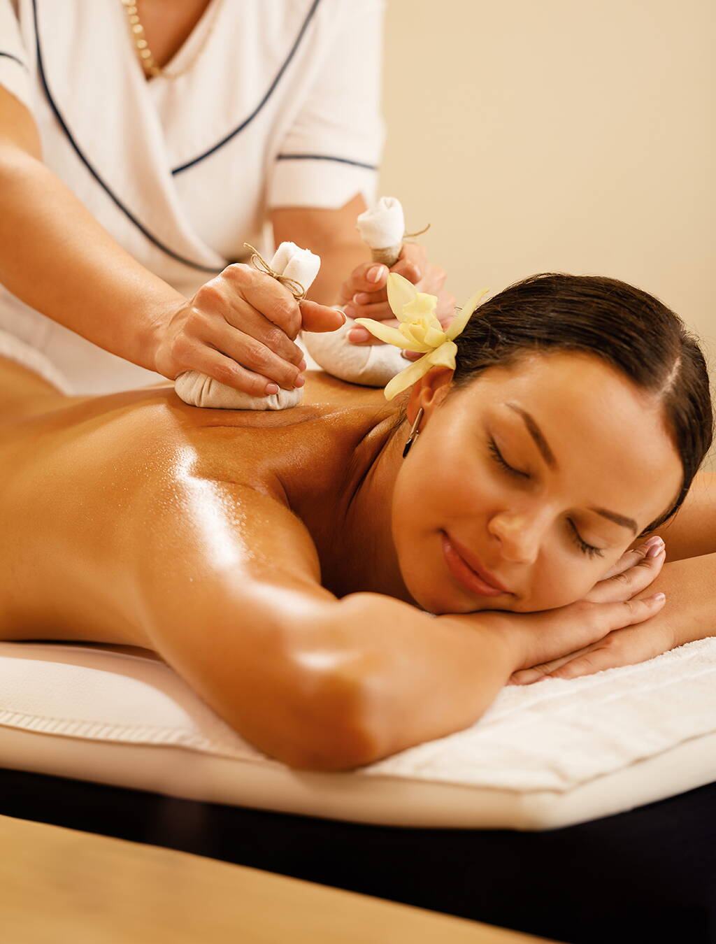 Entspannung für Körper und Geist Bildbeschreibung: Eine schwangere Frau liegt entspannt auf dem Bauch und erhält eine Massage mit duftenden Kräutersäckchen – ein wohltuendes Verwöhnprogramm für werdende Mütter.