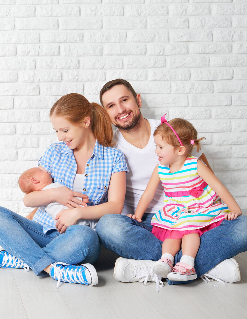 Glückliche vierköpfige Familie in der Schweiz – gemeinsam gut versichert mit PRO LIFE Eine vierköpfige Familie (Vater, Mutter, kleines Mädchen und Baby) sitzt im Schneidersitz am Boden. Das Bild steht für die Sicherheit und den familiären Zusammenhalt, den die Krankenkassenlösung PRO LIFE bietet.