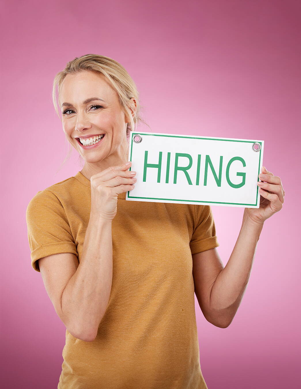 Bereit, etwas zu bewegen? Eine junge Frau hält ein „Hiring“-Schild in die Höhe – ein Zeichen für Offenheit und Neugier auf neue Talente, die unsere Werte teilen und mitgestalten möchten.