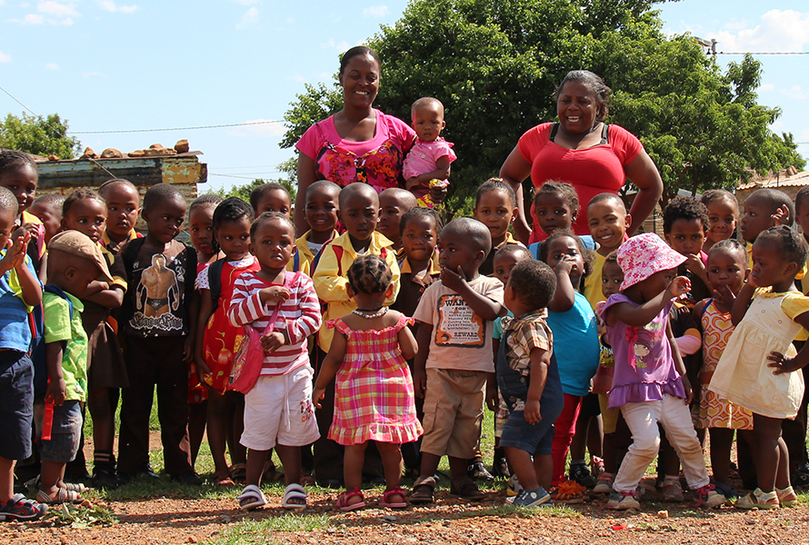 Die Kinder von Nkululeko mit zwei Mitarbeiterinnen – fröhlich, sicher und umsorgt in ihrer neuen Umgebung.