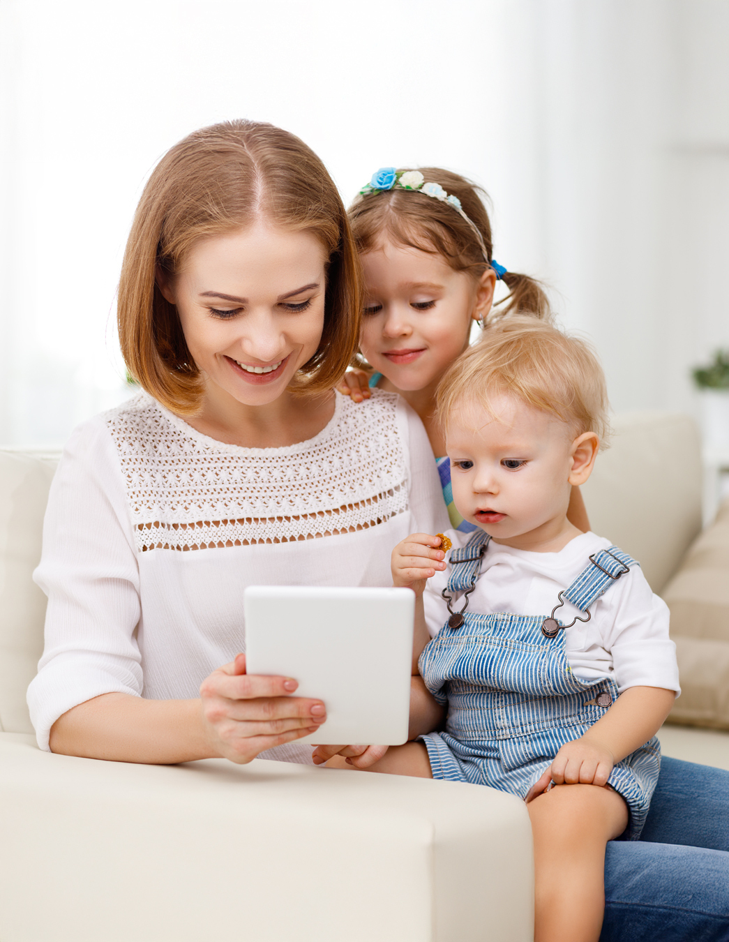 Una giovane madre guarda un tablet con i suoi figli – come socio PRO LIFE, le famiglie hanno accesso a sconti esclusivi sulle assicurazioni complementari.