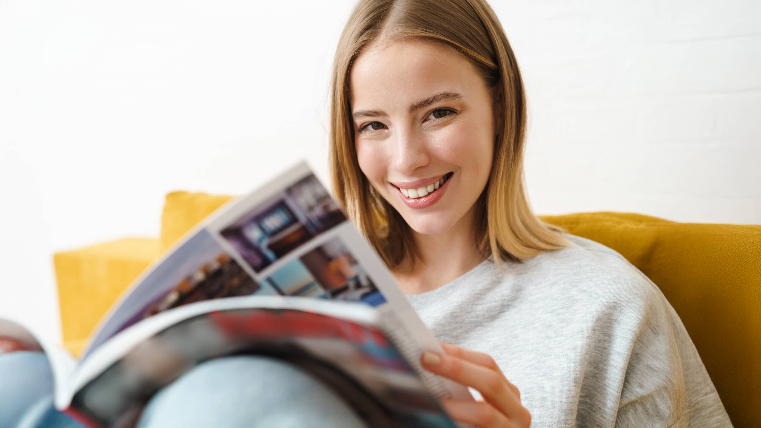 Einblicke, die bewegen Eine junge Frau blättert interessiert in einem Magazin – ein Moment der Inspiration und des Verstehens, was PRO LIFE ausmacht.