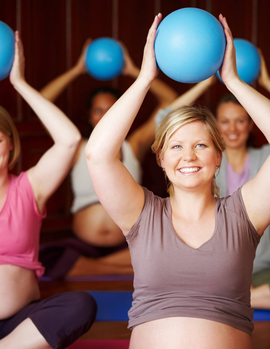 Gemeinsam vorbereitet: Geburtsvorbereitungskurs Schwangere sitzen im Kurs im Schneidersitz und heben Gymnastikbälle – praktisches Üben und Austausch in entspannter Atmosphäre.