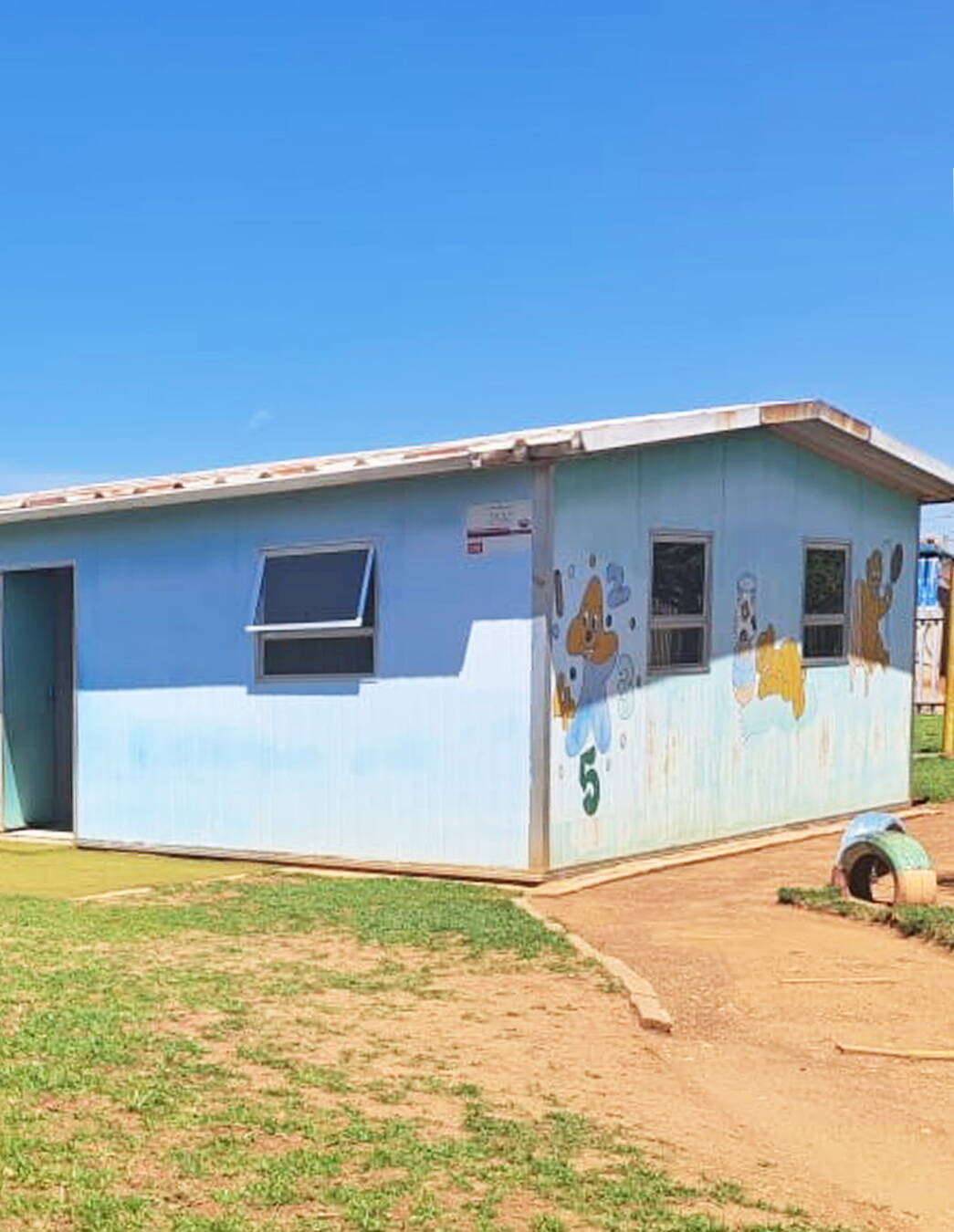 Ein Ort mit Geschichte Das hellblau gestrichene KITA-Gebäude strahlt im Sonnenlicht – ein Symbol für Hoffnung, Bildung und den nachhaltigen Einsatz der Gemeinschaft.