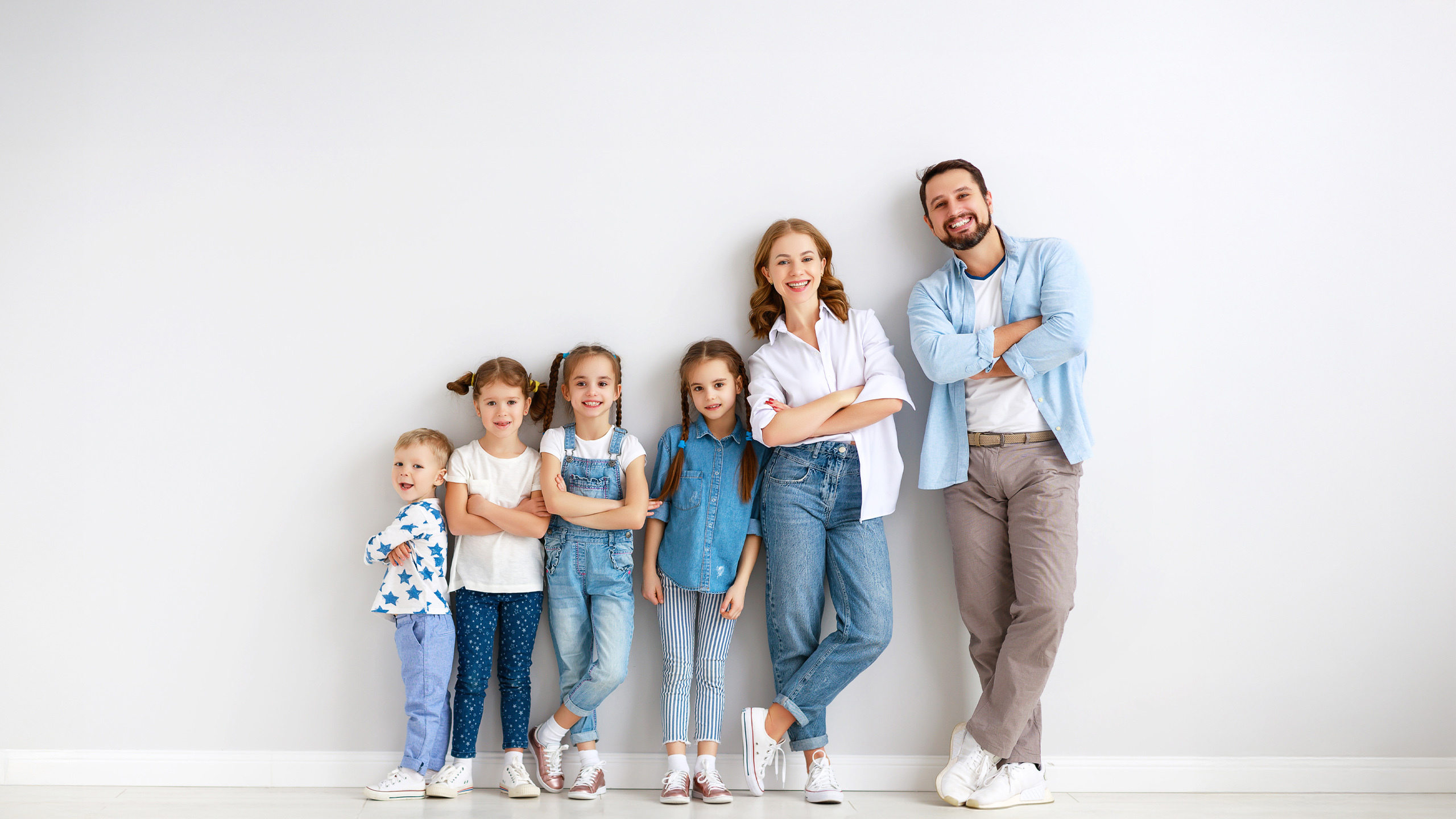 Insieme per la sua famiglia Una coppia con quattro figli appoggiata rilassata a un muro grigio – un’immagine di coesione, fiducia e ciò che conta davvero.