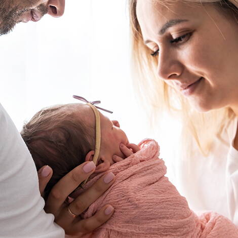 Endlich angekommen Ein glückliches Paar schaut liebevoll auf das Neugeborene in den Armen der Mutter – ein emotionaler Moment nach einer langen Reise voller Vorfreude und Geduld.