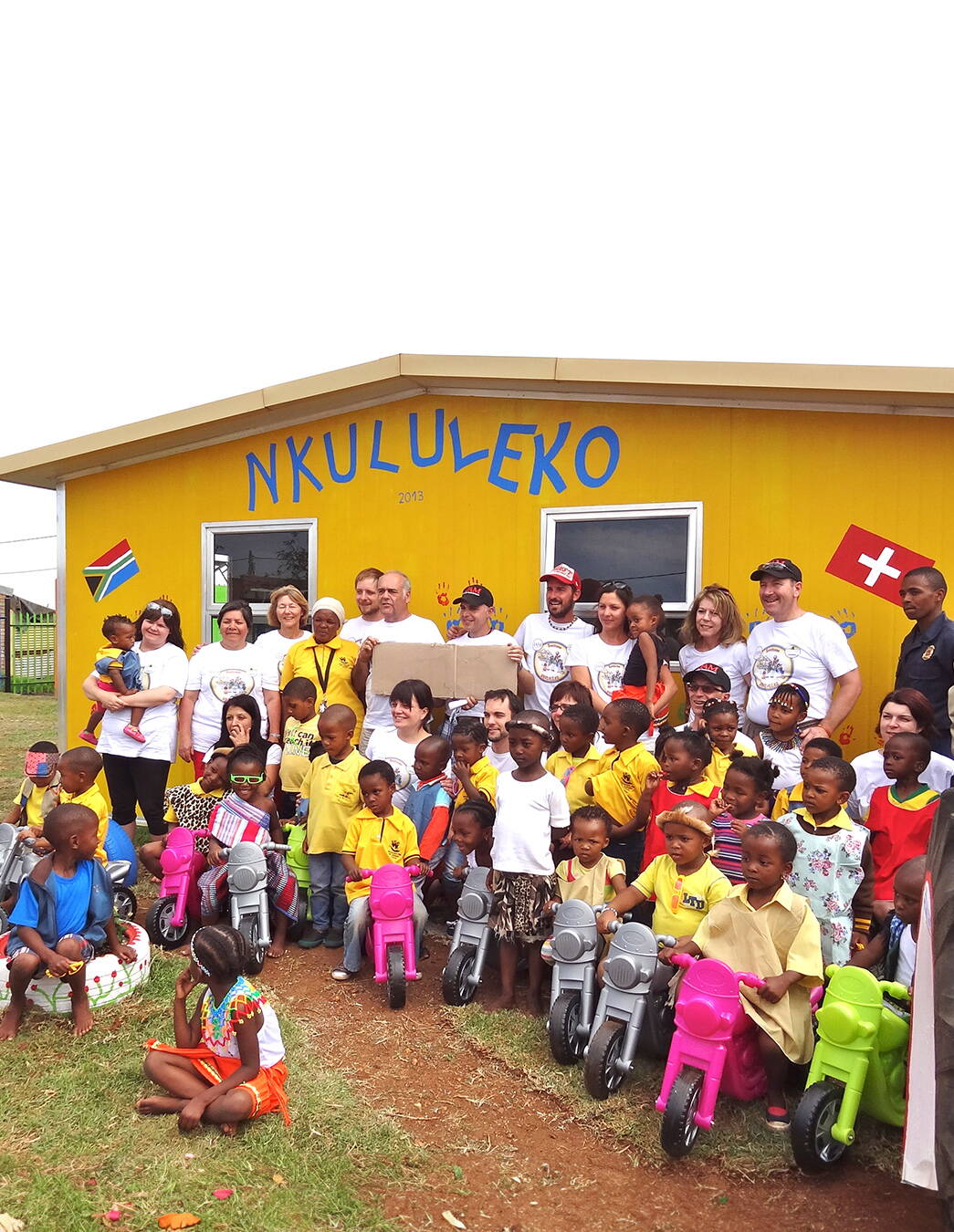 Ein starkes Team für starke Kinder Das Bauteam steht gemeinsam mit den Kindern von Nkululeko stolz vor dem neu errichteten Gebäude – ein Moment voller Hoffnung und Zusammenhalt.