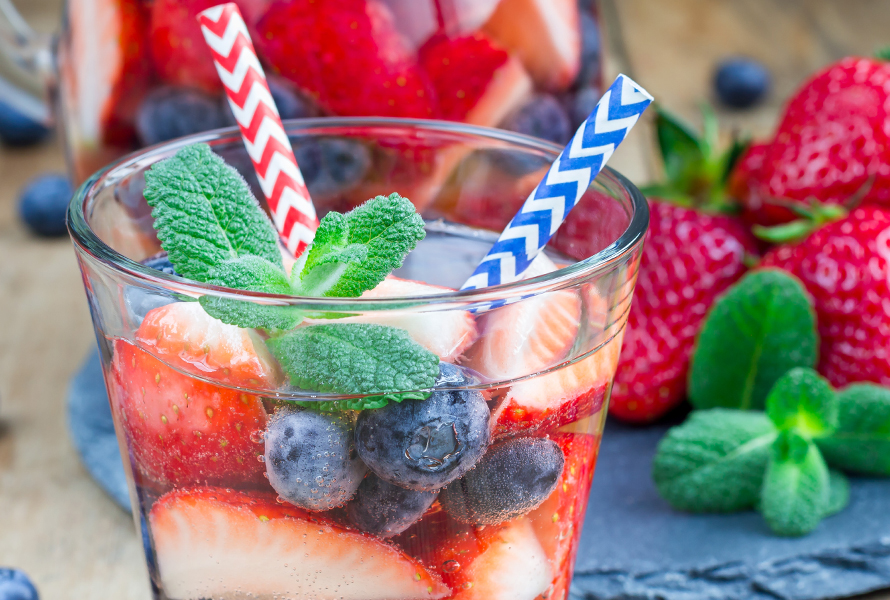 Erfrischend und gesund: Infused Water Ein Glas mit Wasser, gefüllt mit Blaubeeren und Erdbeeren – ein fruchtiger Hingucker und alkoholfreier Drink für Ihre Babyparty.
