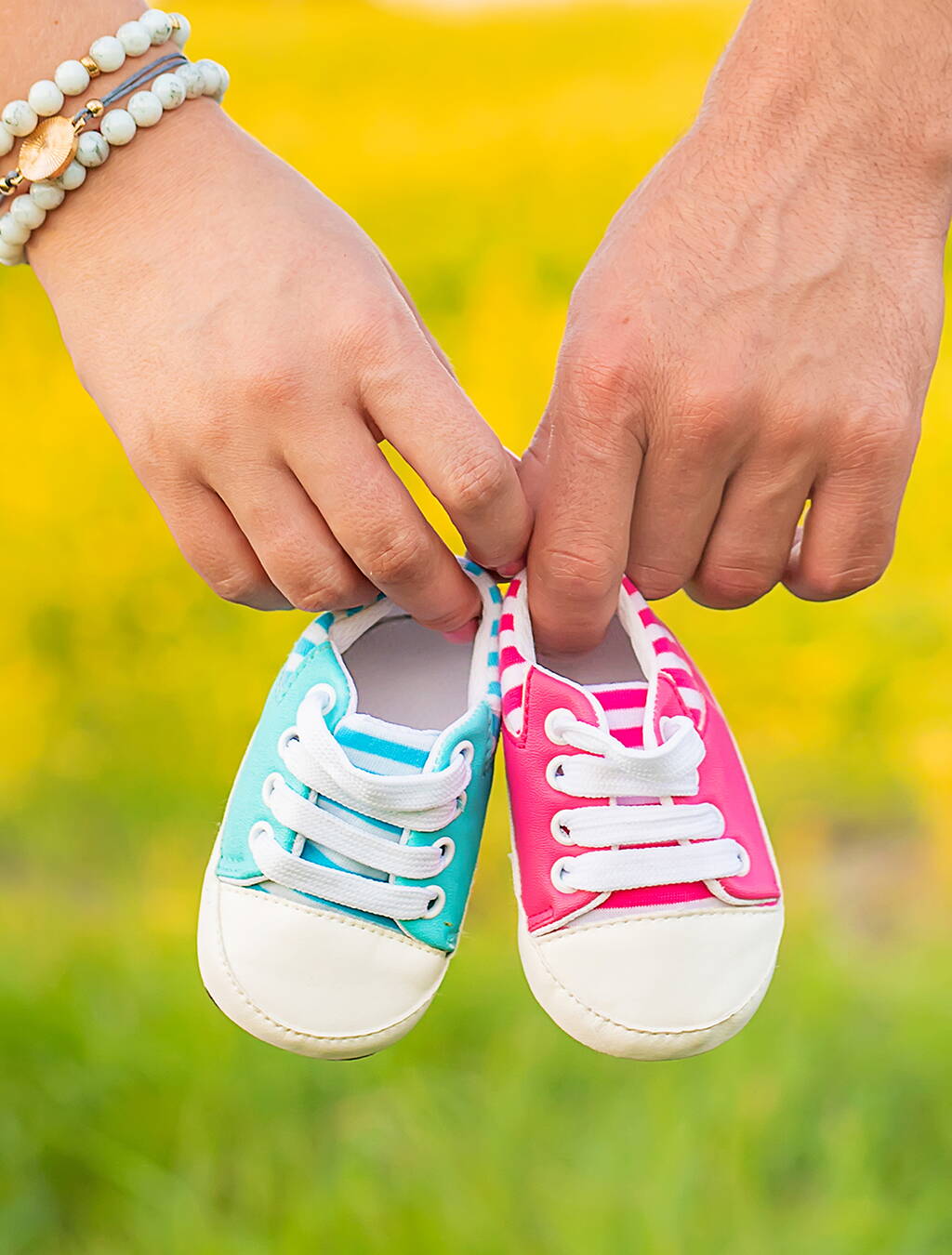 Doppeltes Glück in kleinen Schuhen Zwei Hände halten Babyschuhe in Rosa und Hellblau – ein Symbol für Mehrlingsfreuden und die bevorstehende Geburt.