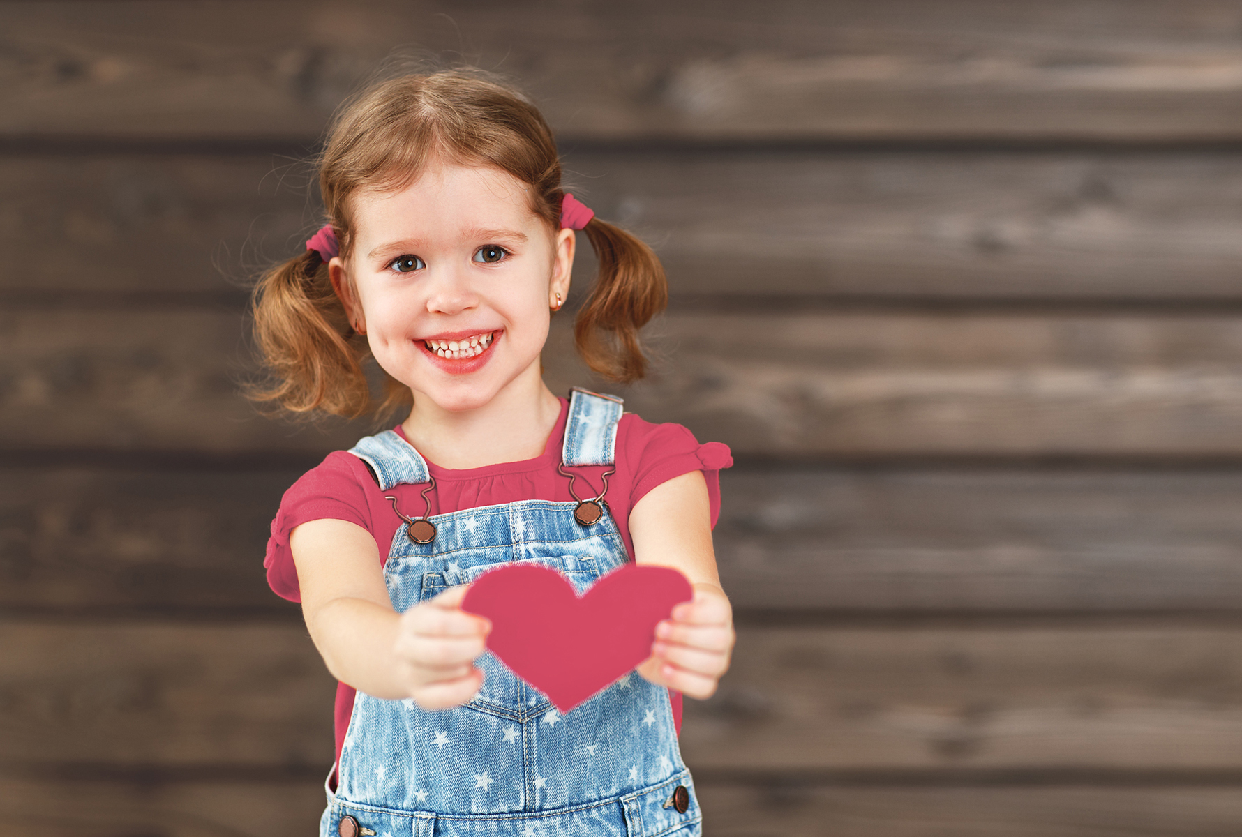 Una bambina porge un cuore verso la fotocamera – un simbolo forte di amore, cura e umanità.