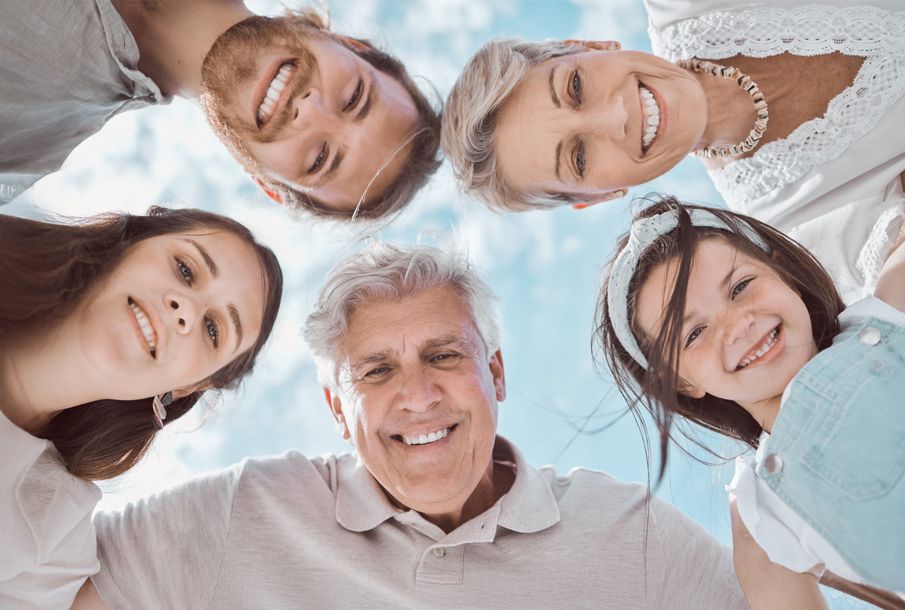 Il nostro impegno Un gruppo eterogeneo di cinque persone si china ridendo verso la fotocamera. L’immagine mostra: la solidarietà unisce – attraverso le generazioni.