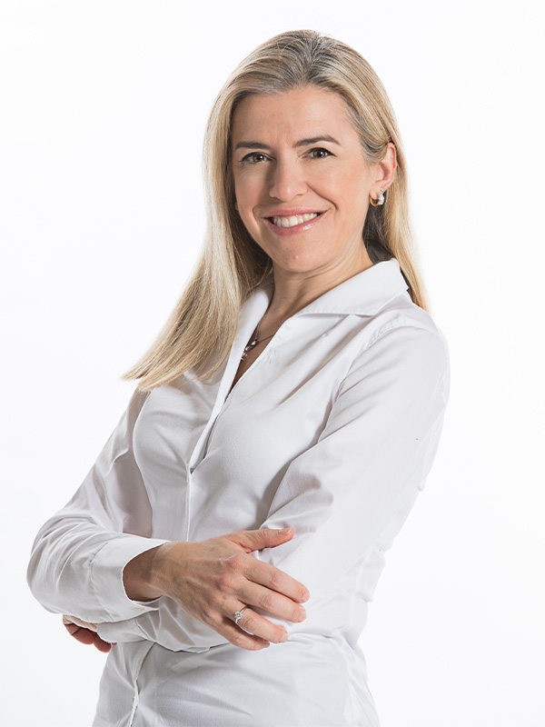 Business-Porträt in weissem Hemd vor hellem Hintergrund, mit verschränkten Armen.