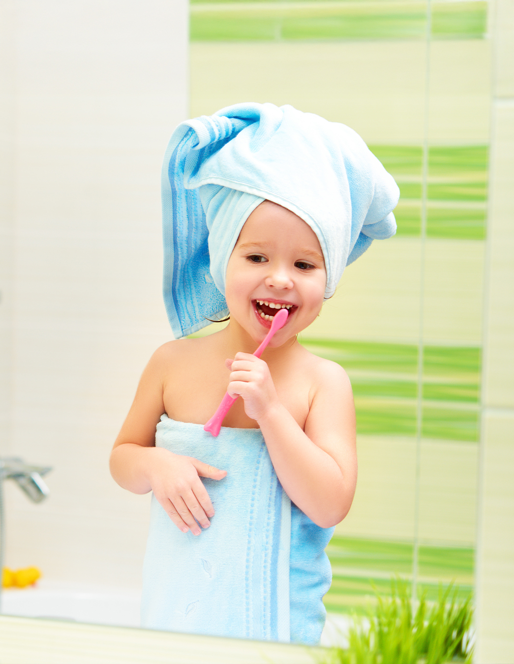 Si inizia presto – anche per lavarsi i denti Una bambina con l’asciugamano in testa si lava i denti con concentrazione – un’immagine di un inizio sano nella vita con il sostegno di PRO LIFE.