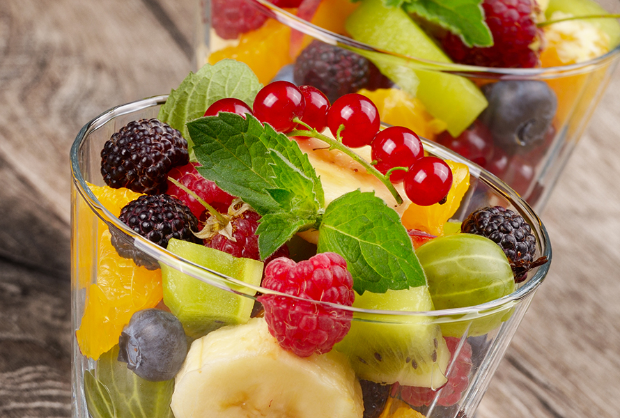 Fruchtsalat in Glasschale Bunte Mischung aus Brombeeren, Himbeeren, Blaubeeren, Johannisbeeren, Banane, Orangenschnitzen und Kiwi – ein ballaststoffreicher Snack gegen Heisshunger.