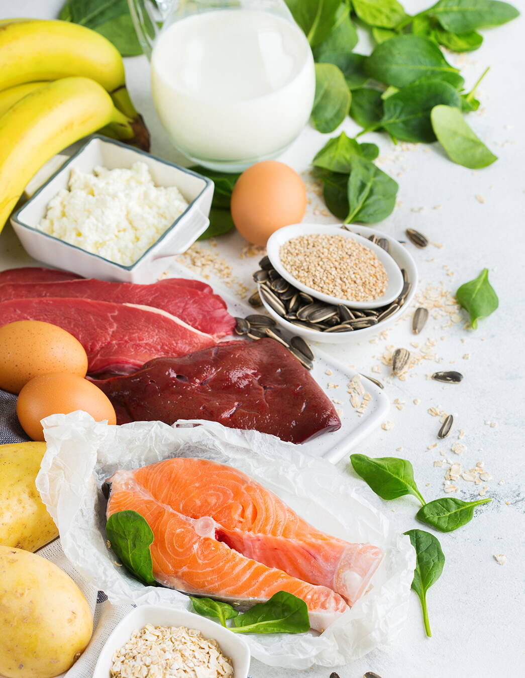 Différents aliments riches en iode comme le saumon, les œufs, le lait, les épinards et les graines illustrent comment tu peux couvrir tes besoins en iode pendant la grossesse de manière équilibrée.
